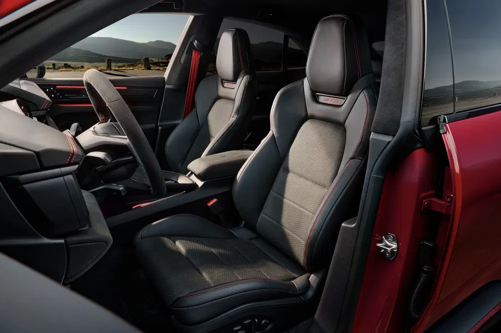 Intérieur Porsche Cayenne 2023 avec sièges sport noirs et surpiqûres rouges distinctives.