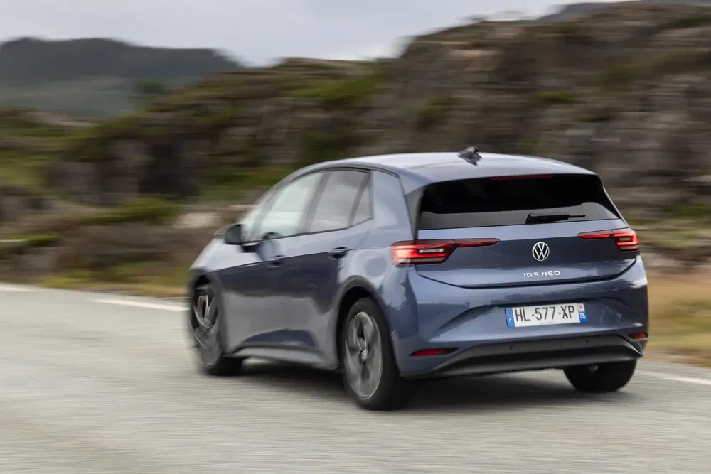 Volkswagen ID.3 Neo rijdt op landweg, elegante achterkant en aerodynamisch profiel.
