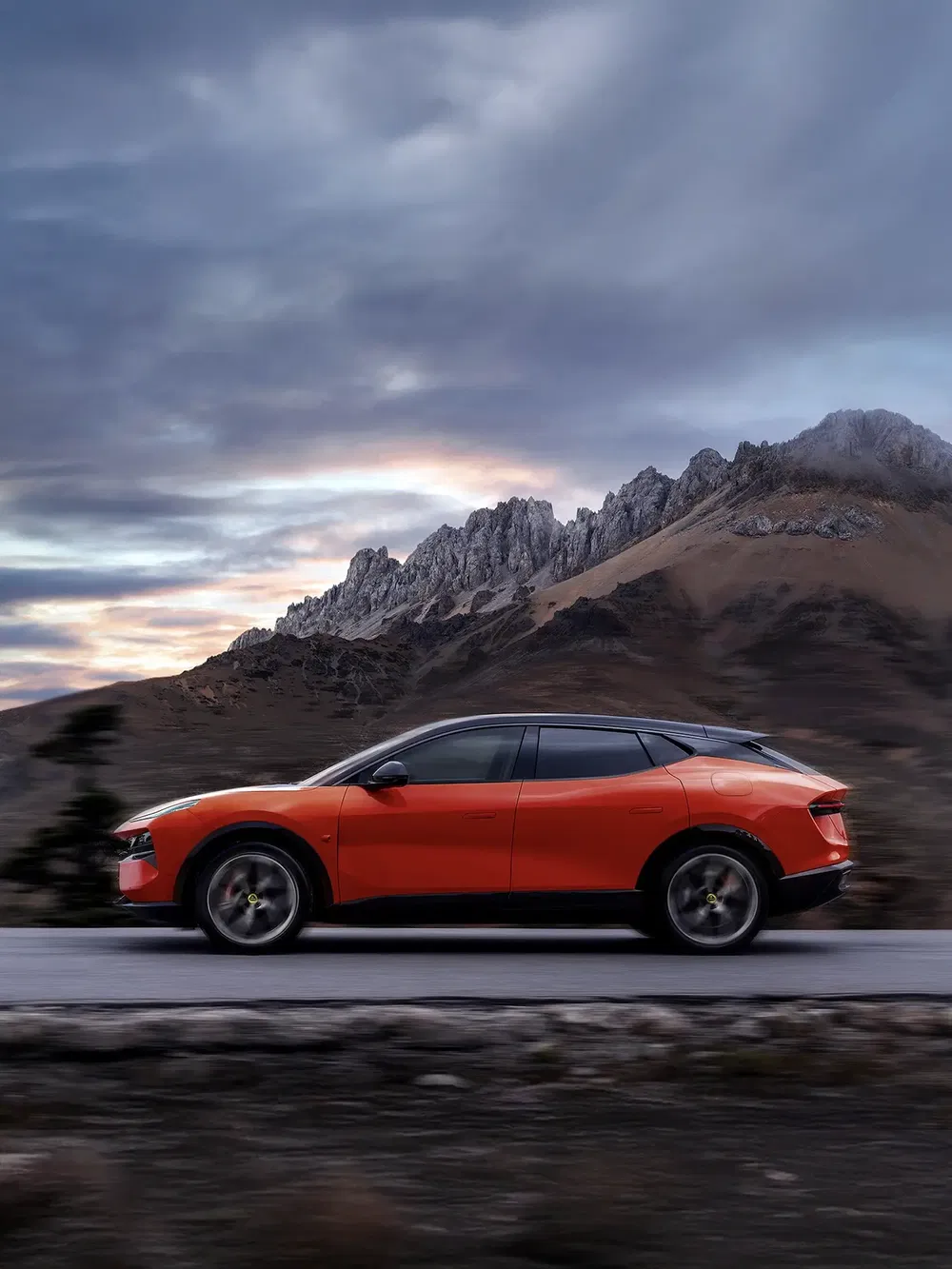 Oranje Ferrari Purosangue rijdt op bergweg met bewolkte lucht.