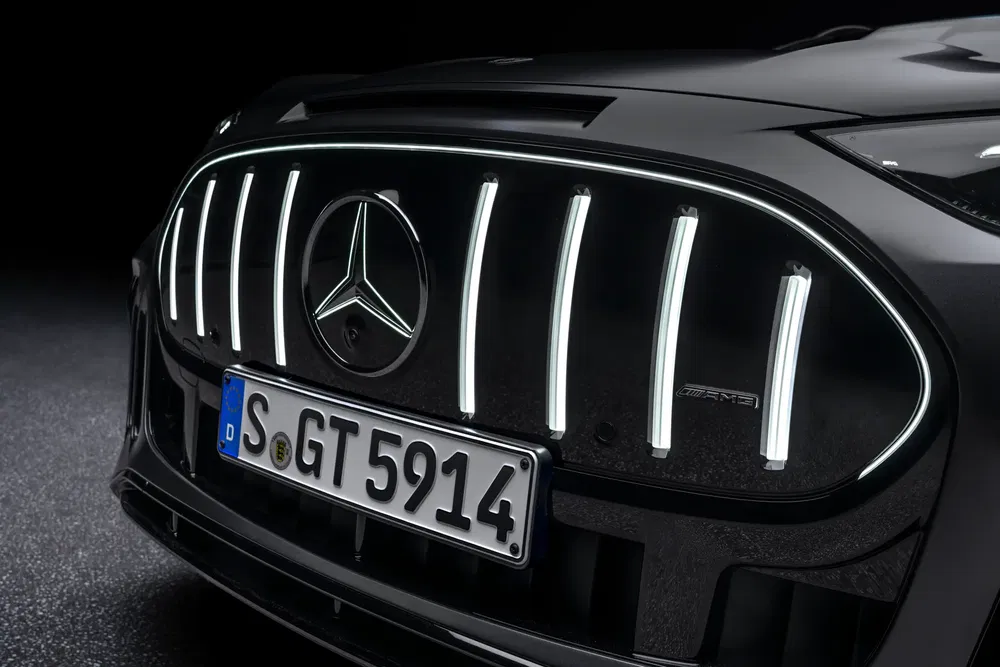 Gros plan sur la calandre illuminée d'une Mercedes-AMG avec logo central et plaque d'immatriculation.