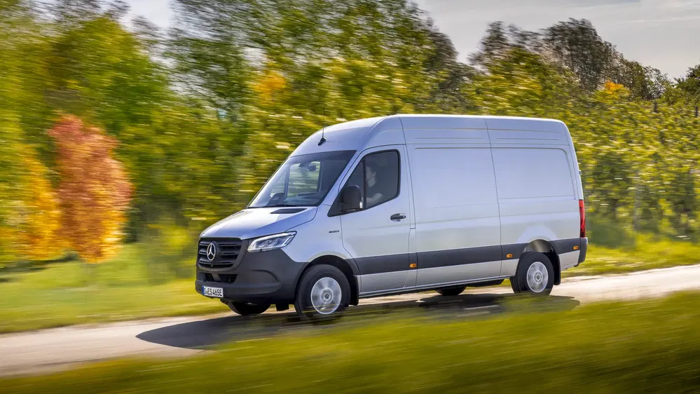 {"fr":"Fourgon Mercedes-Benz Sprinter roulant sur une route bordée d'arbres verts en automne.","nl":"Mercedes-Benz Sprinter bestelwagen rijdt langs met bomen omzoomde weg in de herfst."}
