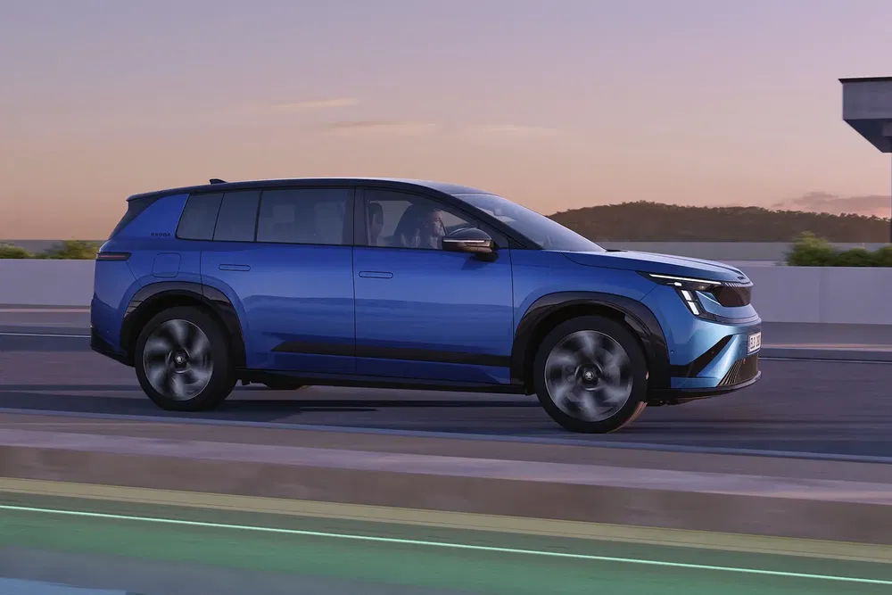 SUV électrique Renault Scenic bleu roulant sur autoroute au coucher du soleil.