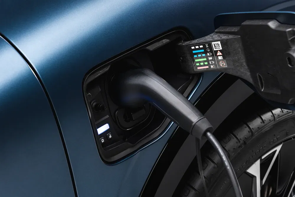 Voiture électrique en chargement, câble branché sur port de charge latéral, modèle moderne.
