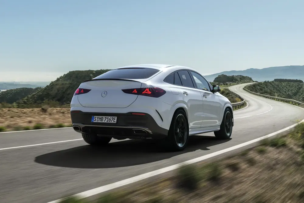 Mercedes GLE coupé blanc sur route sinueuse avec panorama montagneux.