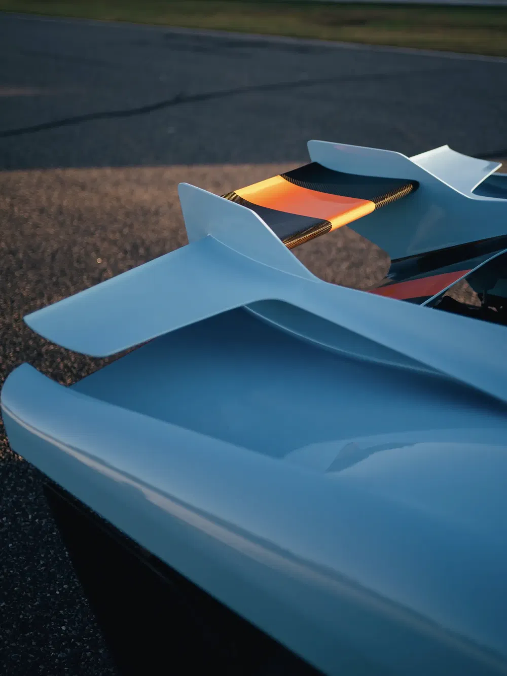Aileron arrière distinctif avec des accents orange et noir sur une voiture de sport moderne.