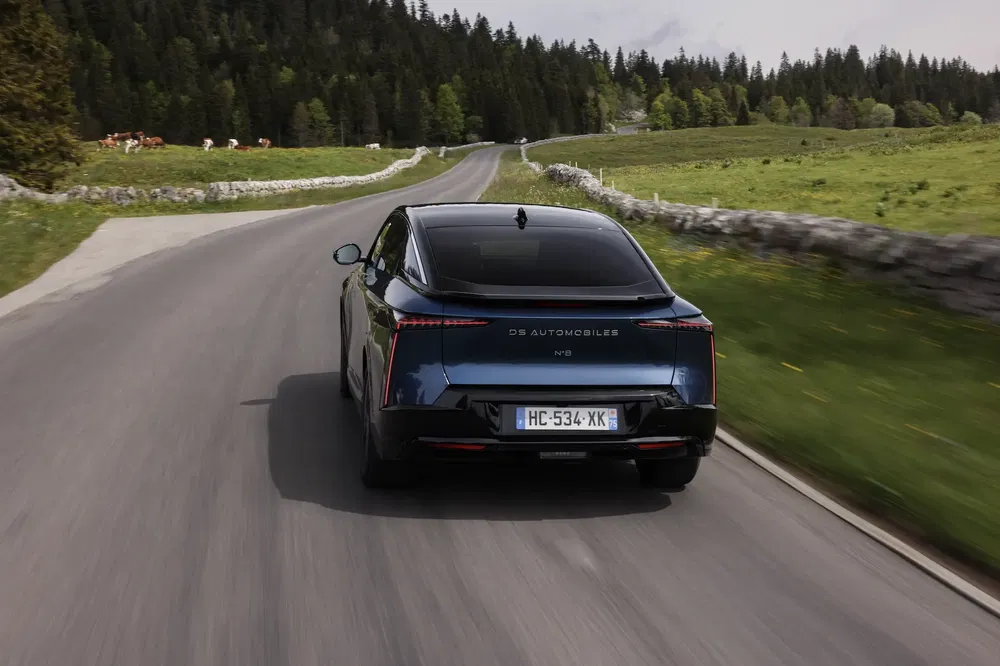 DS Automobiles op kronkelende landelijke weg, groene landschappen op de achtergrond.