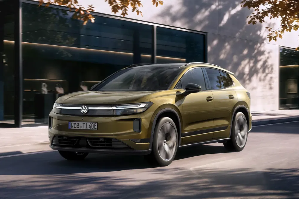 Volkswagen électrique doré roulant en ville près d'immeubles modernes.