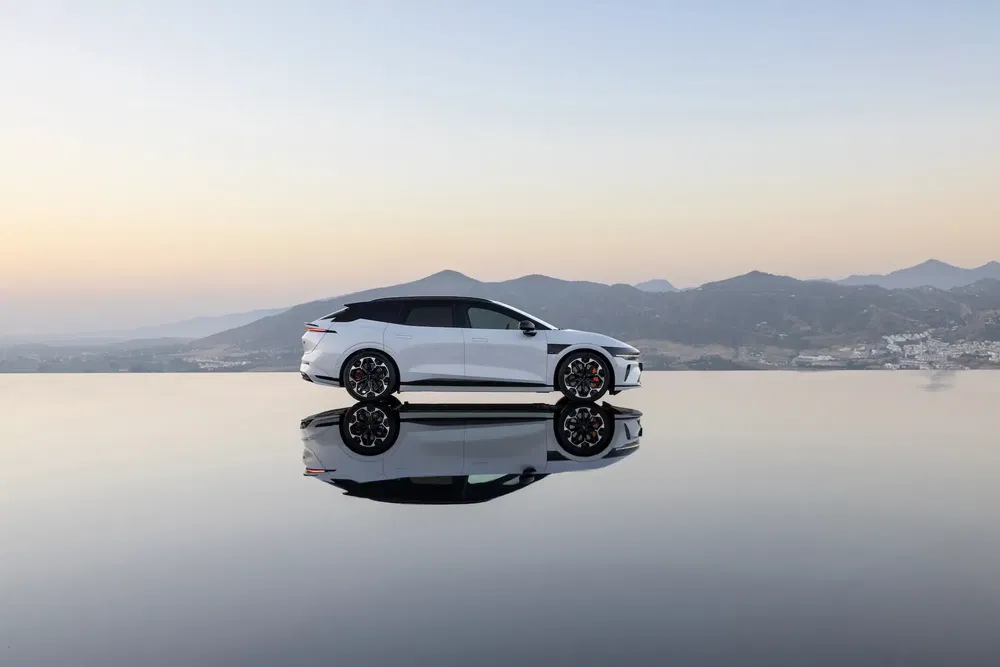 Voiture Kia EV6 blanche reflétée sur une surface d'eau, montagnes en arrière-plan.