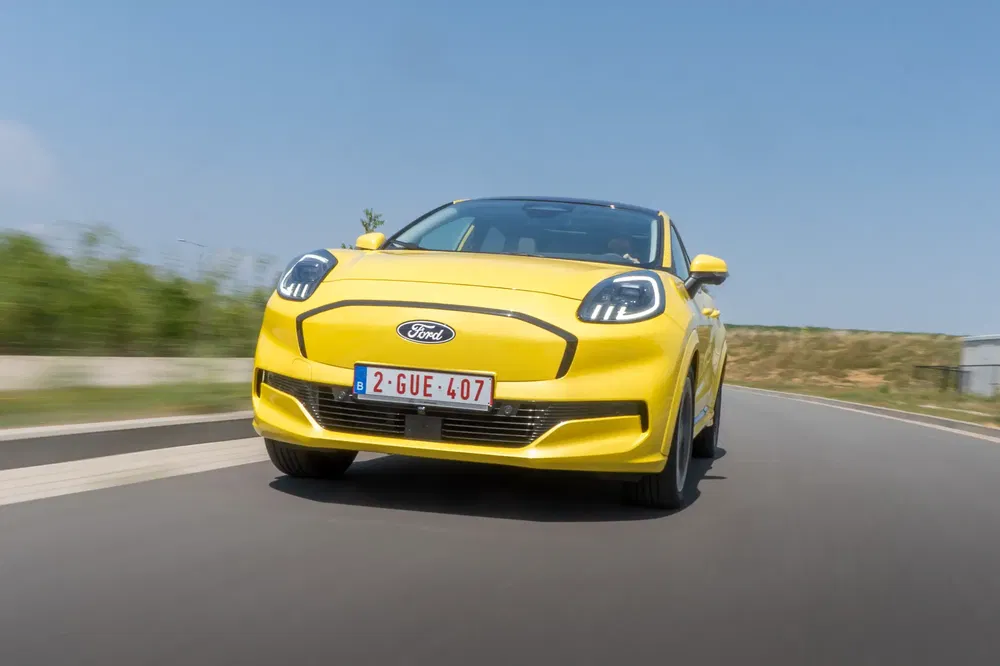 Gele Ford auto op weg, opvallende LED-verlichting, Belgische nummerplaat zichtbaar.