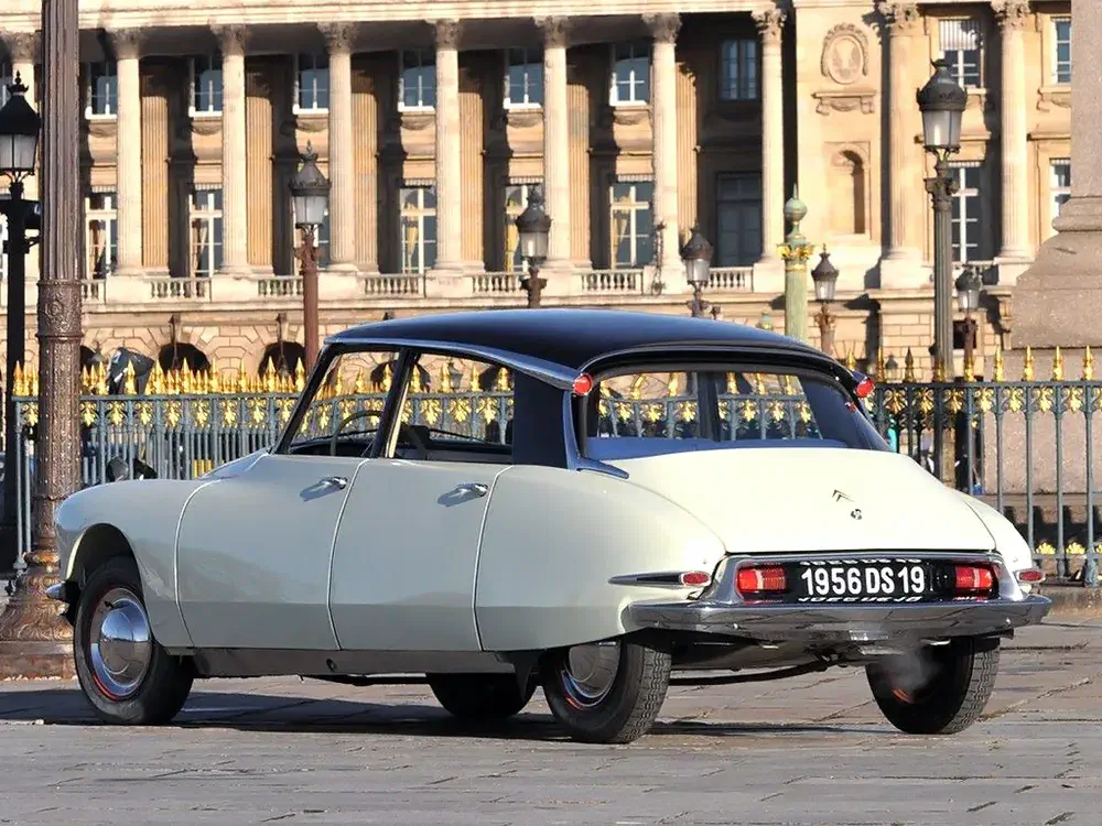 Citroën DS 1956 stationnée devant un bâtiment historique, emblématique du design automobile français.
