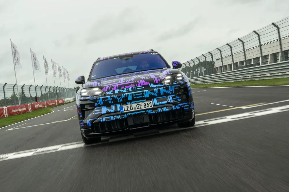 Elektrische Porsche Macan prototype op racecircuit, blauwe en paarse patronen.