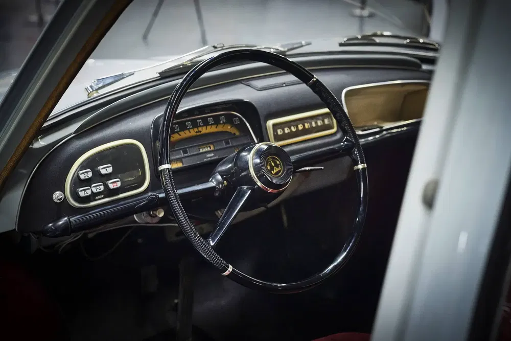 Intérieur d'une Renault Dauphine avec un tableau de bord vintage et volant classique.