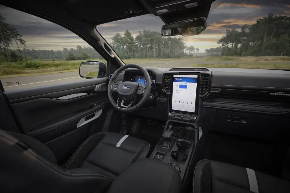 Intérieur moderne d'un Ford avec écran tactile et volant élégant sur fond de nature.