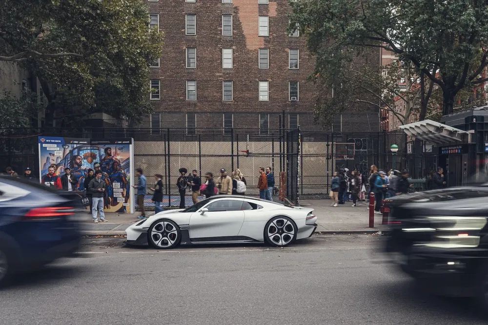 Witte Porsche Mission R elektrische auto geparkeerd in de stad met voetgangers op de achtergrond.