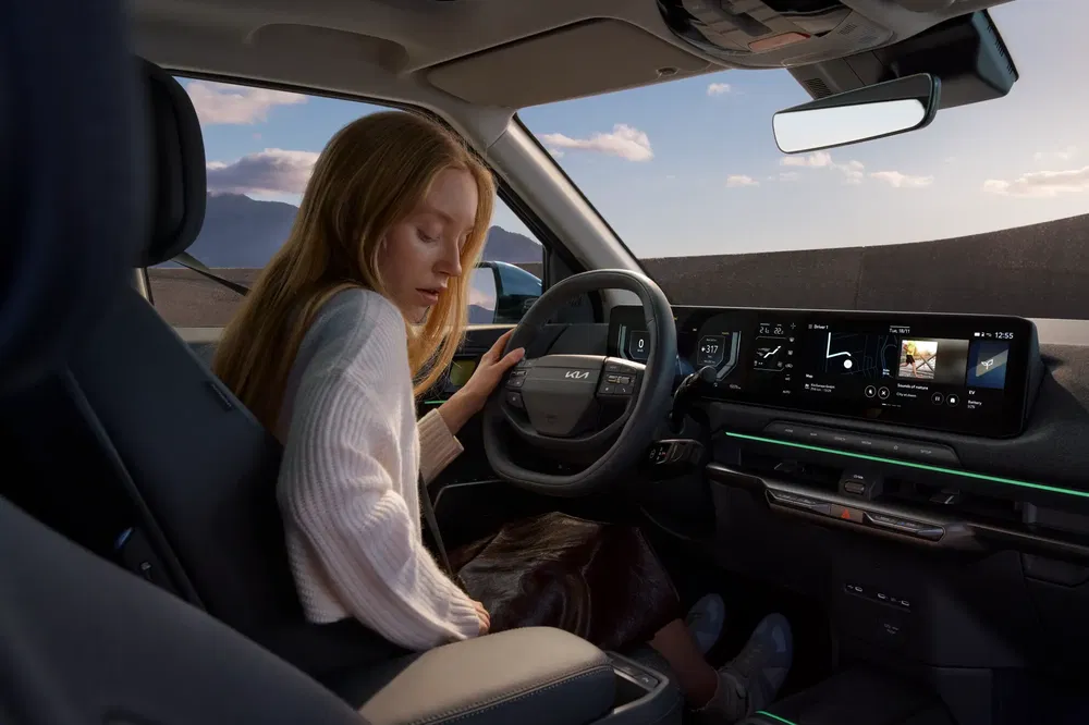 Modern interieur van een Kia met digitaal dashboard, rijden in zonnige buitenomgeving.