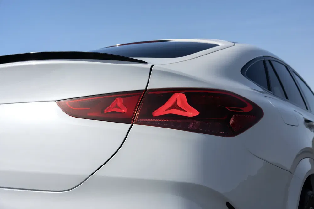 Vue arrière d'une voiture avec feux arrière distinctifs en forme de flèches rouges.