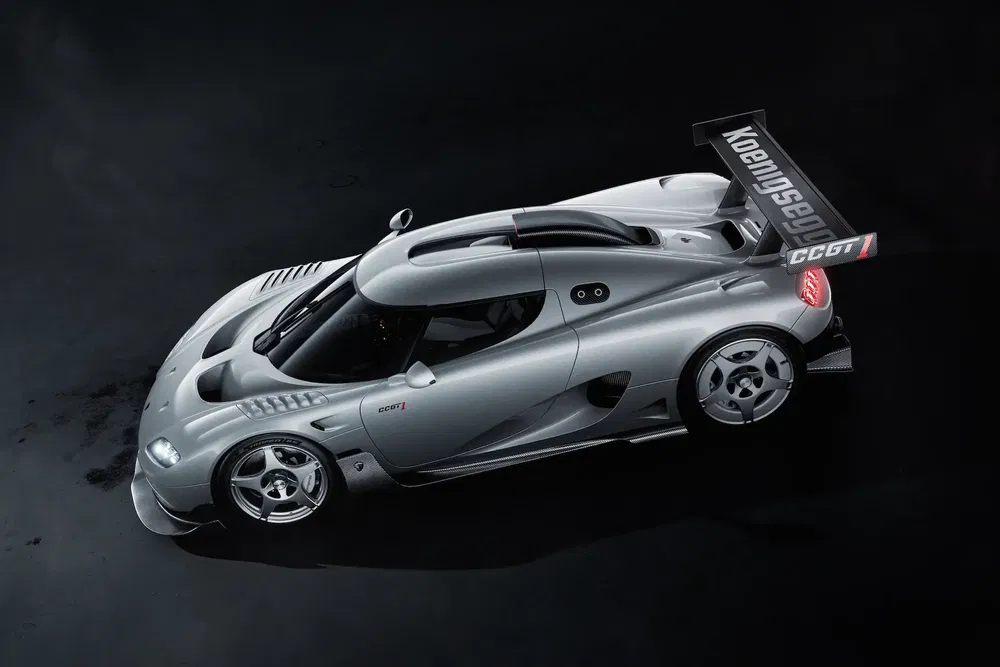 Voiture de sport Koenigsegg CC GT argentée avec aileron imposant sur fond noir.