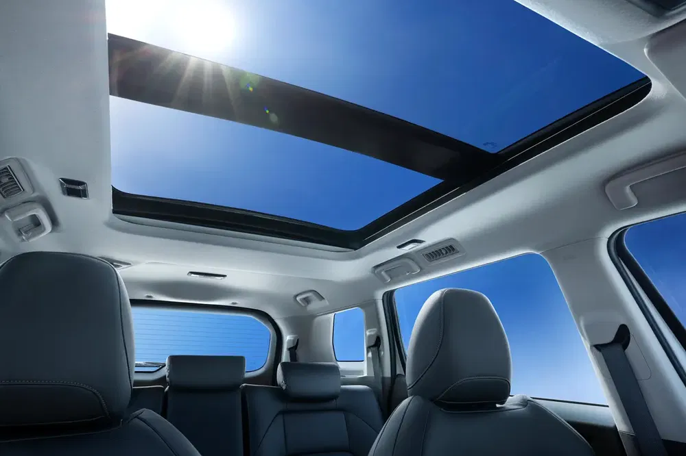 Intérieur voiture avec toit ouvrant panoramique, ciel bleu en arrière-plan.