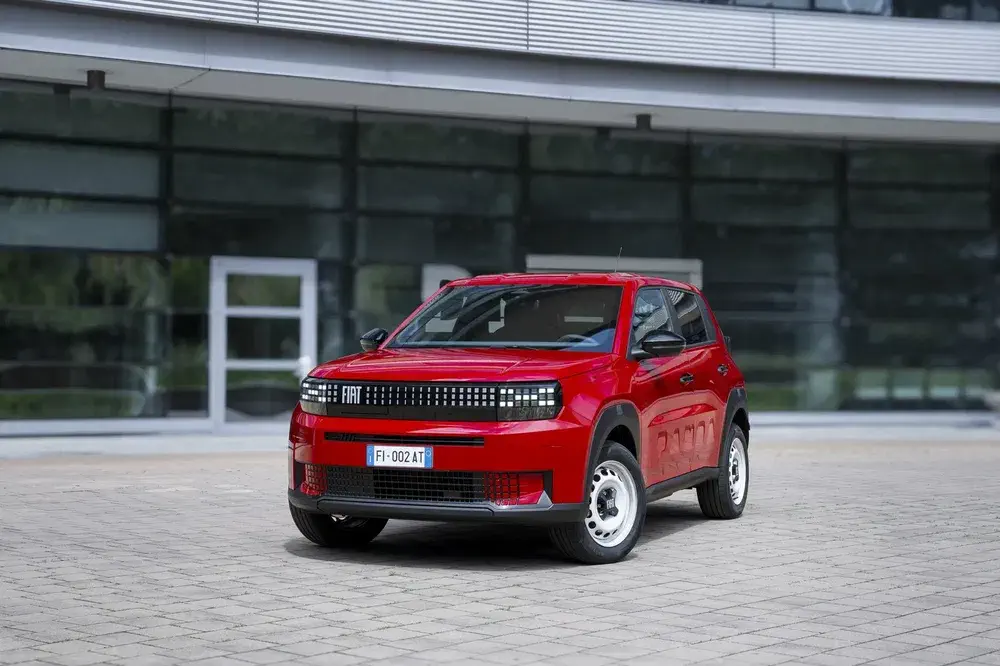 Fiat Panda rouge moderne devant bâtiment vitré, design compact et urbain.