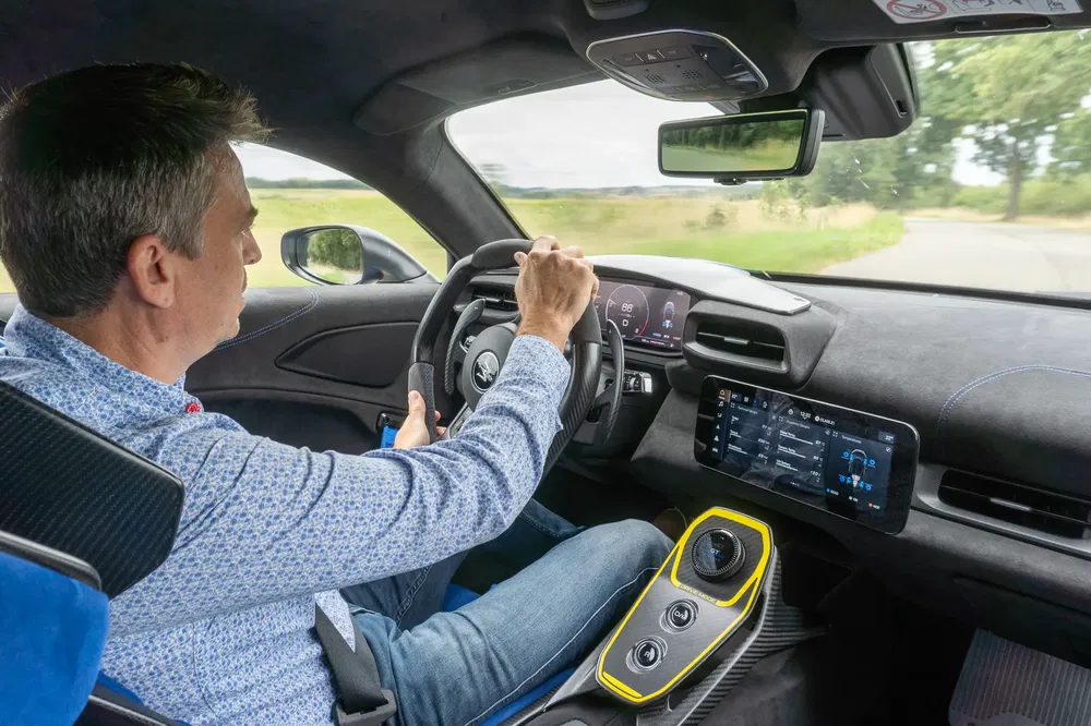 Conducteur à l'intérieur de l'Alpine A110, en route sur une route de campagne.