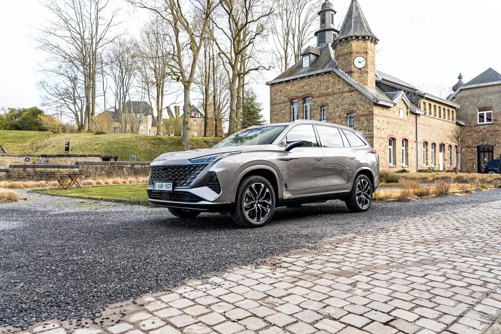 Moderne SUV geparkeerd voor bakstenen landhuis, vredige en elegante omgeving.