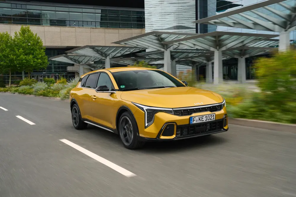 Kia ProCeed jaune vibrant roule sur route moderne, design dynamique et avant-garde.