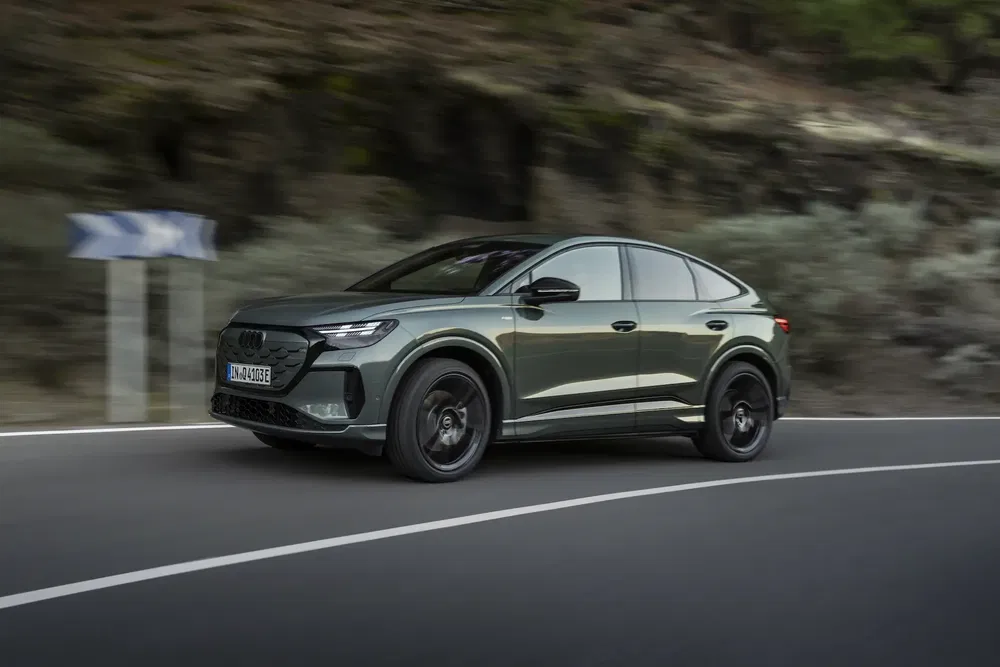 Audi Q4 e-tron coupé roulant sur une route sinueuse en milieu naturel.