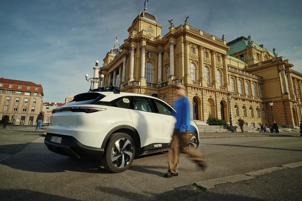 SUV blanc devant un bâtiment historique, personne marchant à proximité, ambiance urbaine.