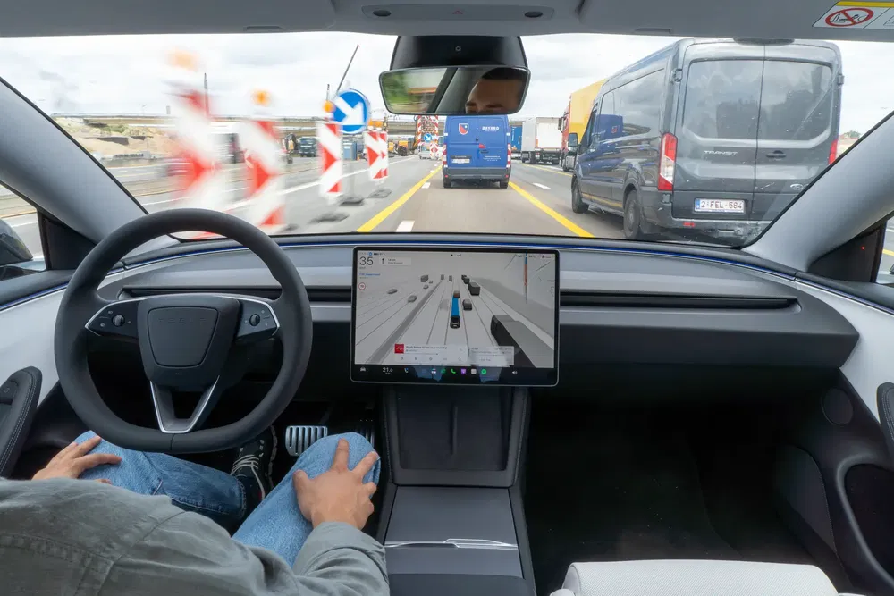 Voiture autonome en autopilote sur autoroute avec écran de navigation central, circulation dense.