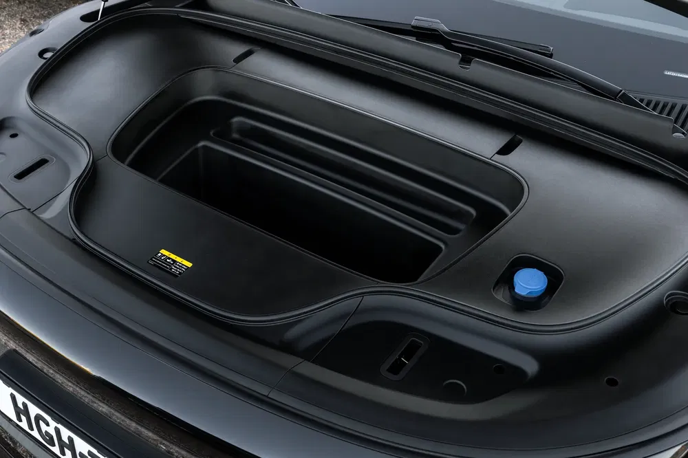 Coffre avant de voiture électrique avec compartiment de rangement noir spacieux et bouchon bleu.