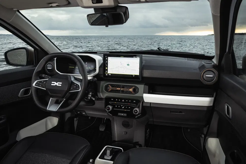 Modern interieur van Dacia Jogger, stuur en navigatiescherm, uitzicht op de zee.