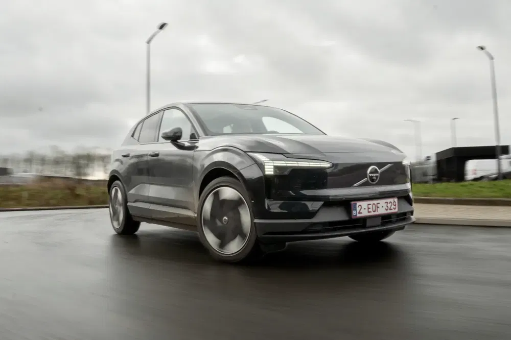 Volvo électrique roulant sur route mouillée sous ciel couvert.