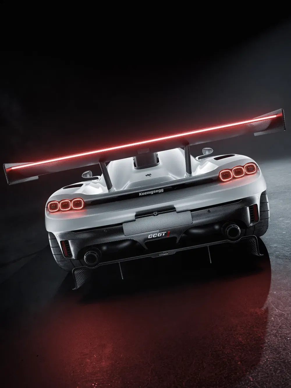 Vue arrière d'une Koenigsegg CC GT blanche avec grand aileron, éclairage rouge distinctif.