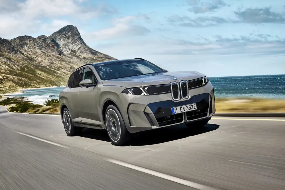 BMW SUV moderne sur route côtière, mer et montagnes en arrière-plan.