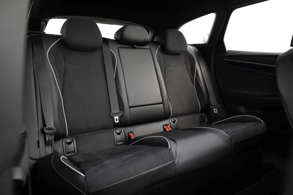 Intérieur de voiture moderne, banquettes arrière en cuir noir avec coutures blanches contrastantes.