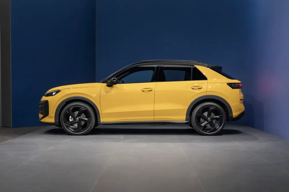 SUV Audi Q4 e-tron jaune profil stationné sur un fond bleu industriel.