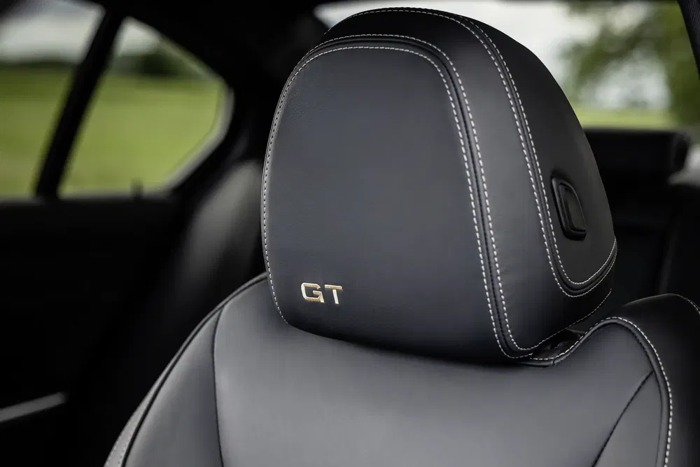 Appuie-tête cuir noir avec logo GT brodé, intérieur de voiture élégante.
