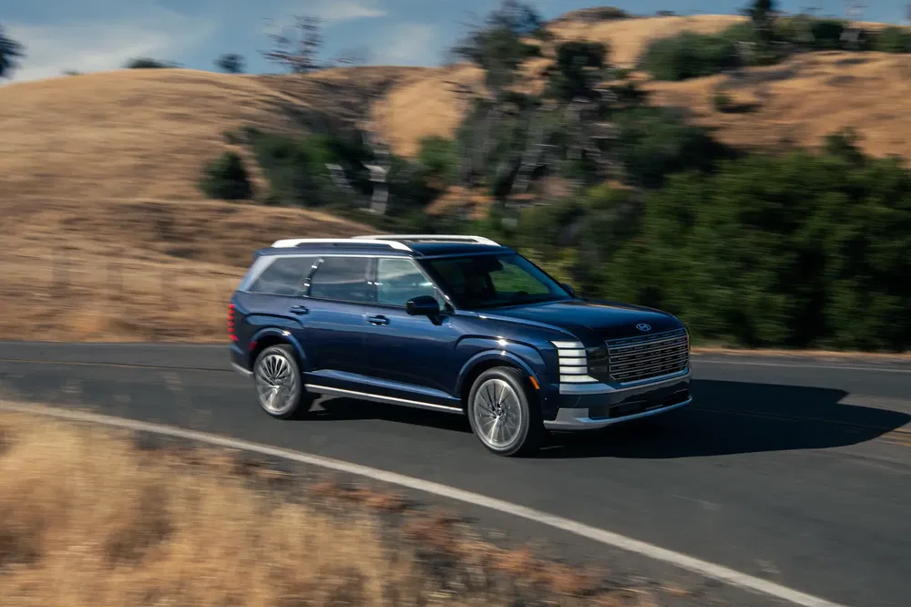{"fr":"SUV Kia EV9 bleu sur route sinueuse dans paysage rural ensoleillé.","nl":"Blauwe Kia EV9 SUV op kronkelende weg in zonnig, landelijk landschap."}
