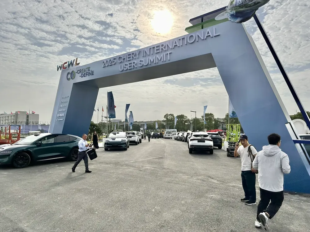 Ingang van de Chery Internationale Gebruikers Summit 2025 met moderne elektrische auto's.