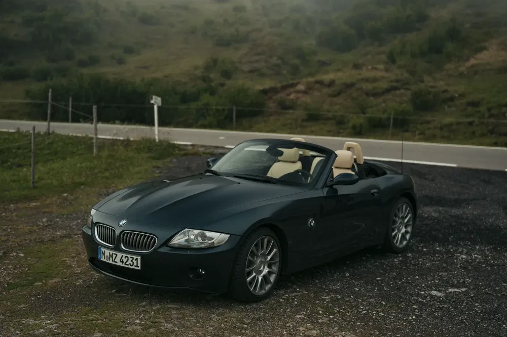 Zwarte BMW Z4 cabriolet geparkeerd op een bergweg, ideaal voor een schilderachtige rit.