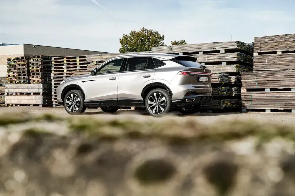 Moderne SUV geparkeerd voor stapels hout, industriële achtergrond.