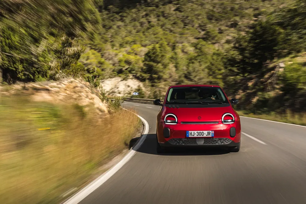 Fiat Panda 2023 rouge sur route sinueuse entourée de verdure.