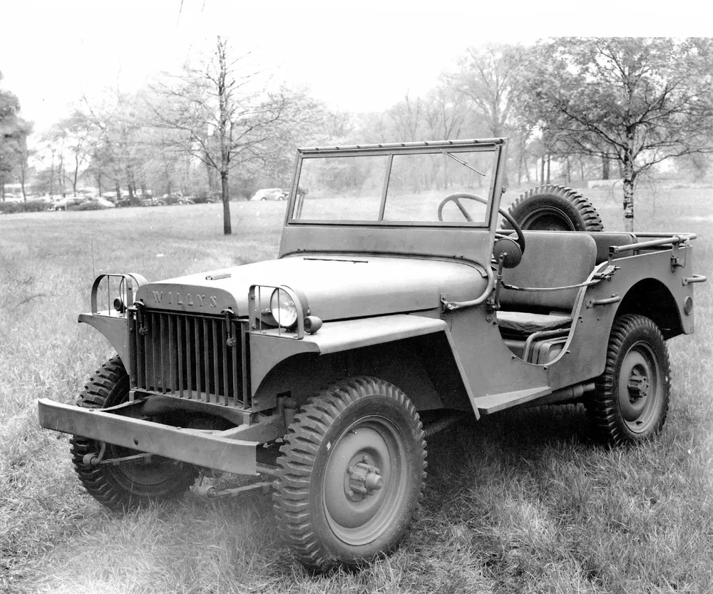 Klassieke Willys Jeep geparkeerd op gras, met reservewiel achterop.