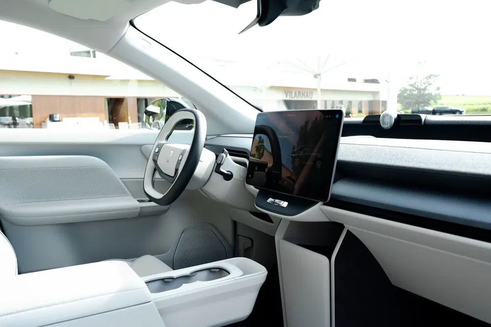 Intérieur d'une Tesla moderne avec un tableau de bord minimaliste et écran tactile central.