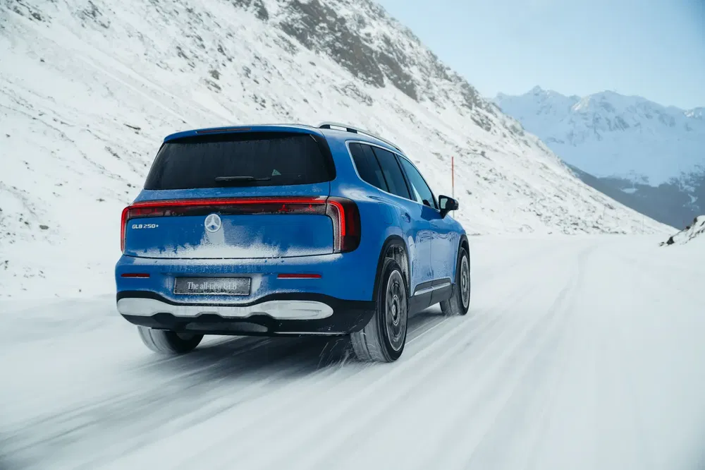 Mercedes-Benz GLB 250 roulant sur une route enneigée dans un paysage montagneux hivernal.