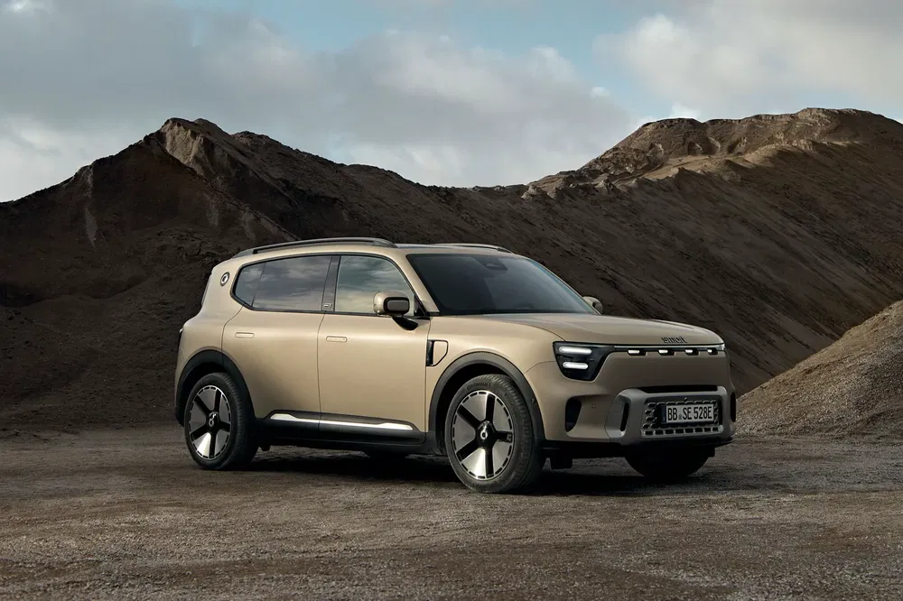 Elektrische Kia SUV in beige op bergachtig terrein, modern en robuust ontwerp.