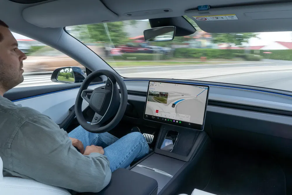 Conducteur dans une voiture Tesla Model 3 utilisant la fonction de conduite autonome.
