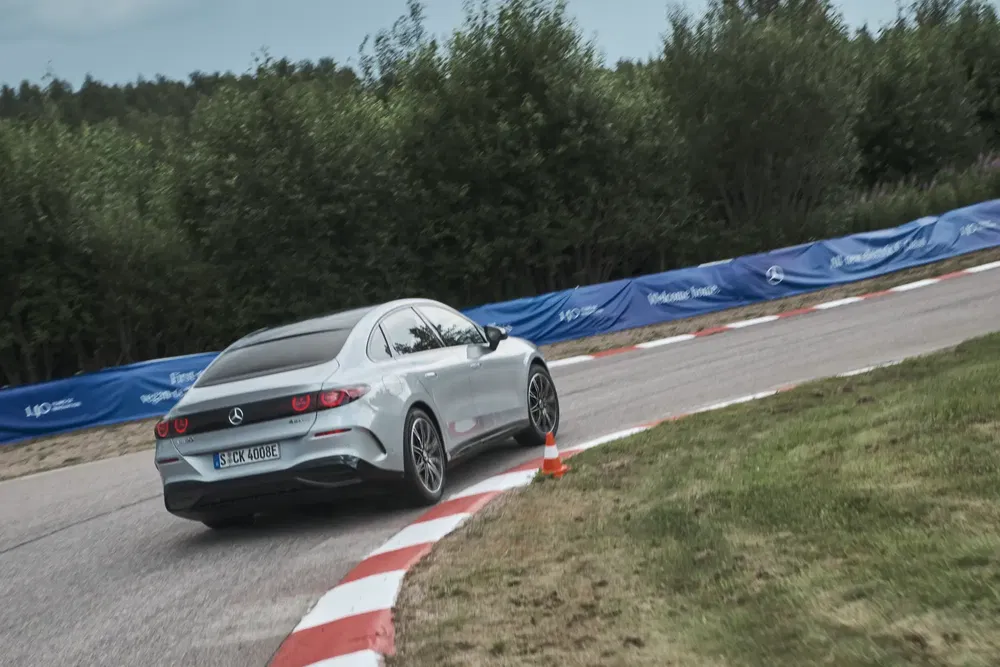 Mercedes-Benz EV tourne sur piste courbée entourée de verdure, testant sa performance.