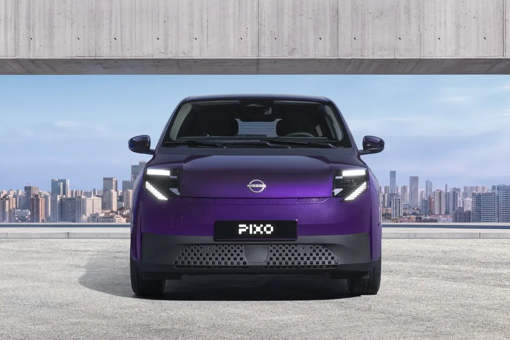 Nissan Pixo violet urbain, vue avant avec paysage urbain en arrière-plan.
