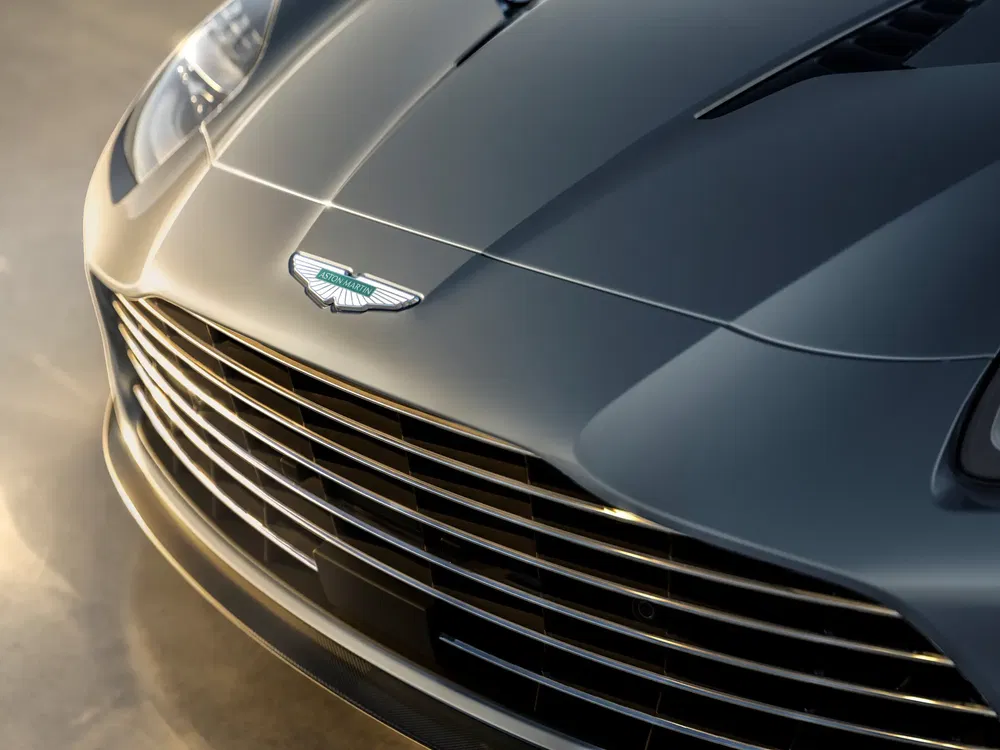 Gros plan calandre Aston Martin grise, logo emblématique et design élégant.